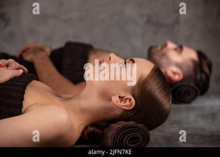 Giovane uomo e donna sdraiati sui lettini da massaggio presso il lussuoso centro benessere e termale Foto Stock