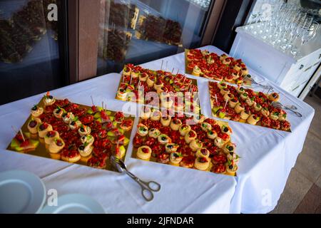 Diverse tartine con salmone affumicato, pomodori cetrioli ciliegia e mozzarella serviti su un tavolo. Foto di alta qualità Foto Stock