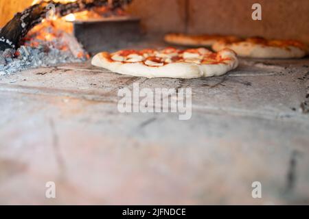 pizza tradizionale napoletana che si inforna forno a legna con spazio copia, sullo sfondo fiamme e legno marchiatura, pizza margherita con basilico Foto Stock