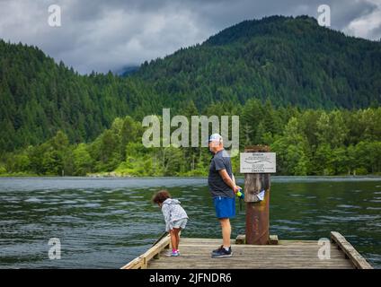 Nipote e suo nonno che giocano sul lago nel parco. Nonno con nipote godendo il tempo insieme al lago. Foto di viaggio, selettiva Foto Stock