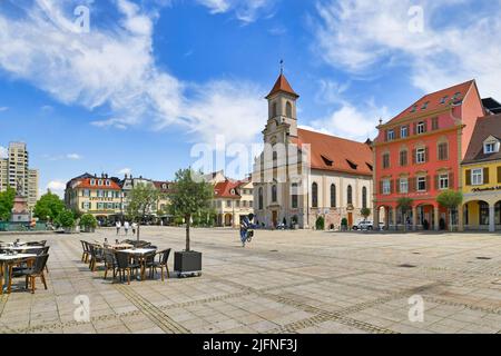 Ludwigsburg, Germania - Luglio 2022: Piazza del mercato con tavoli da ristorante all'aperto e la chiesa 'Zur Heiligsten Dreieinigkeit' Foto Stock