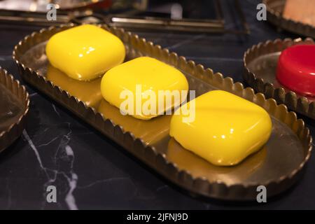 Tre torte di forma quadrata su un vassoio coperto con glassa gialla. Foto Stock