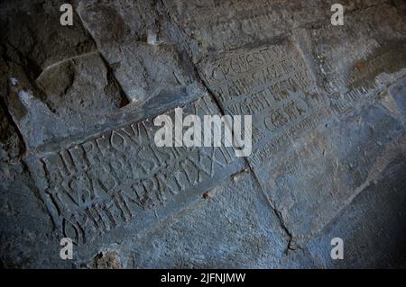 Sul muro del chiostro che si affaccia sulla chiesa si possono vedere molti necrologi funebri scolpiti nelle pietre. Il Real Monasterio de San Juan de la P. Foto Stock