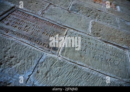 Sul muro del chiostro che si affaccia sulla chiesa si possono vedere molti necrologi funebri scolpiti nelle pietre. Il Real Monasterio de San Juan de la P. Foto Stock