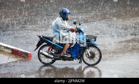 Un tassista motociclista corre in una pioggia pesante su una motocicletta Foto Stock