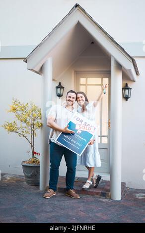 Giovane coppia caucasica che tiene le chiavi della casa mentre si sposta nel nuovo appartamento. Felice uomo e donna in possesso per la vendita e venduto segno fuori casa mentre Foto Stock