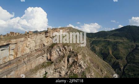 Vista aerea di una splendida roccia enorme con le nuvole sullo sfondo. Azione. Volare sopra le montagne con piste verdi. Foto Stock