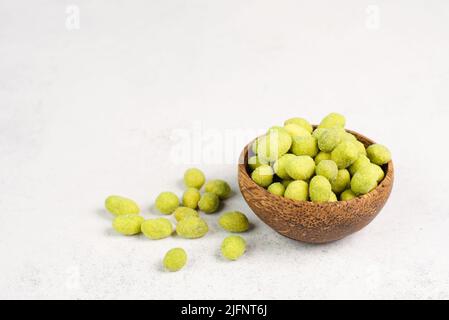 Mucchio di arachidi verdi rivestite con wasabi in una ciotola, snack piccante, cibo orientale Foto Stock