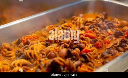 Polpo bambino , salsa di pomodoro .Polpo stufato con pomodori -ricetta italiana chiamata ,guazzetto, moscardini in umido ,polpo alla Luciana ricetta tipica Foto Stock