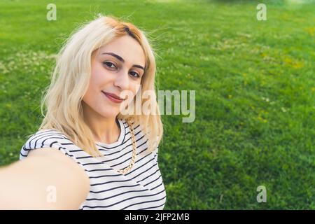 selfie di una giovane ragazza bionda al parco. medio primo piano spazio esterno copia. Foto di alta qualità Foto Stock