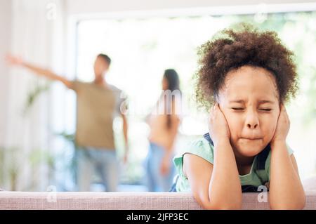 Ive ottenuto usato per bloccarli fuori. Shot di una bambina che copre le sue orecchie, mentre i suoi genitori discutono sullo sfondo. Foto Stock