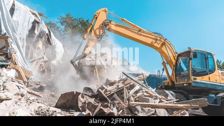 Edificio di demolizione. Escavatore distruggere vecchia casa. Foto Stock