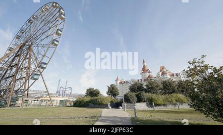 Un grande castello in un parco divertimenti.Action.Un grande parco con una ruota panoramica e montagne russe, si può vedere il parco e gli alberi. Foto Stock