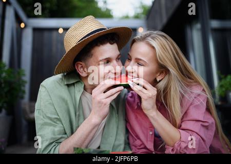 Allegro giovane coppia in amore mangiare fetta di cocomero insieme Foto Stock