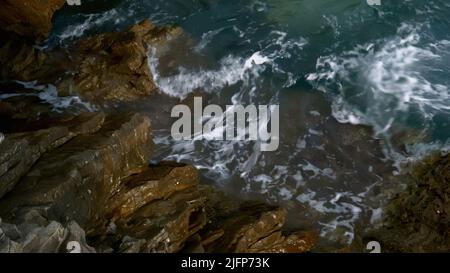 Vista mare da un drone.Creative.Blue onde impulsive che battono contro grandi rocce grigie situate vicino alla riva. Foto Stock