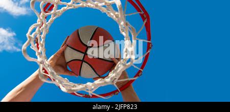 le mani del giocatore di basket gettano la palla nel cerchio, successo. Design poster orizzontale. Intestazione banner Web, spazio di copia. Foto Stock