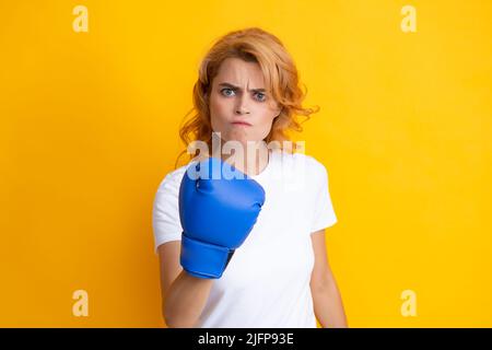 Donna arrabbiata in guanti da boxe isolato su sfondo giallo. Foto Stock