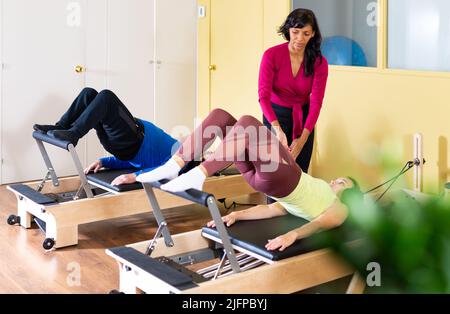 Ispanica femmina pilates istruttore aiutare la donna che si esercita sul reformer Foto Stock