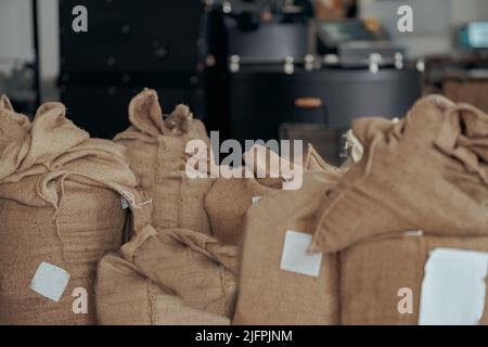 Sacchi pieni di chicchi di caffè torrefatto in fabbrica pronti per la vendita Foto Stock