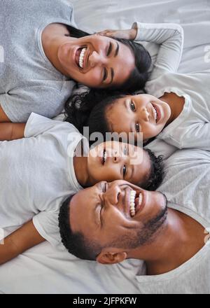 Una famiglia felice è solo un cielo più vecchio. Scatto di una bella famiglia giovane che si unisce a letto insieme. Foto Stock