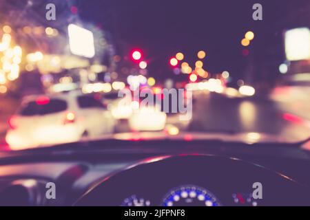 Immagine sfocata di auto interne con luci bokeh da ingorghi di traffico di notte. Vista dall'interno di una macchina Foto Stock