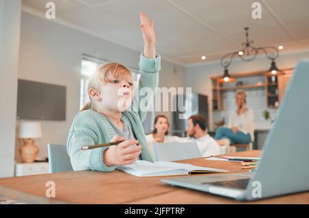 Ragazza di scuola domestica con la sua mano nell'aria. Cute bambino caucasico utilizzando un portatile per frequentare le lezioni a distanza. Porre e rispondere alle domande in classe Foto Stock