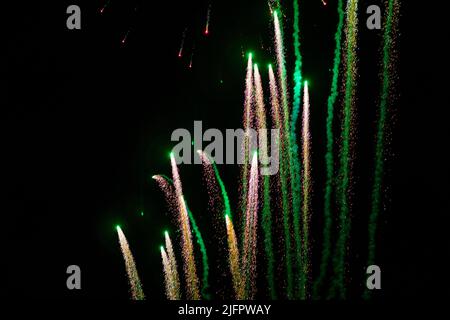 Volando verso l'alto, volli di fuochi d'artificio festosi in giallo e verde, sullo sfondo del cielo notturno. Foto di alta qualità Foto Stock