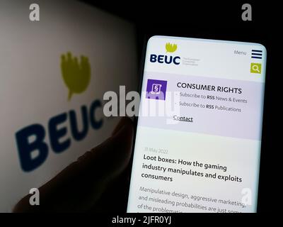 Persona che detiene il cellulare con il sito web di Bureau Europeen des Unions de Consommateurs (BEUC) su schermo con logo. Concentrarsi sul centro del display del telefono. Foto Stock