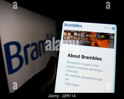 Persona che detiene il cellulare con sito web della società australiana di servizi Brambles Limited sullo schermo con logo. Concentrarsi sul centro del display del telefono. Foto Stock