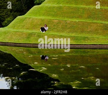 Una giovane donna che riposa sulle celle dell'opera di vita - un paesaggio di Charles Jencks a Jupiter Artland, Lothian Foto Stock