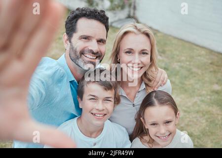 Dire famiglia. Scatto di una famiglia che prende un selfie nel giardino a casa. Foto Stock