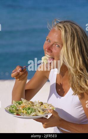 bella bionda capelli giovane donna mangiare insalata Foto Stock
