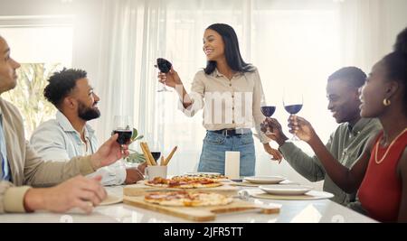 Ai miei amici che sono al mio fianco per il bene e il male. Shot di un gruppo di persone che condividono un brindisi intorno al tavolo da pranzo in una casa. Foto Stock