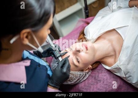 Beauty master misurare le sopracciglia con i calibri prima del trucco permanente. Foto Stock