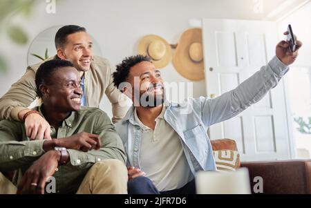 I miei amici i vostri amici Un buon momento. Scatto di un uomo che prende un selfie con i suoi due amici a casa. Foto Stock