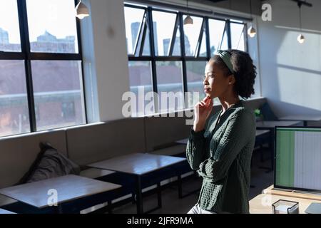 Giovane donna d'affari afroamericana con mano sul mento in ufficio Foto Stock