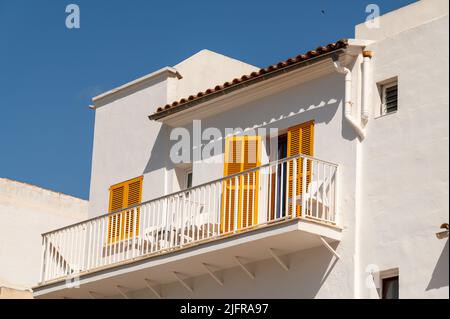 Cala Ratjada, Maiorca, Spagna; 25th giugno 2022: Casa bianca con persiane gialle sul lungomare di Cala Ratjada Foto Stock