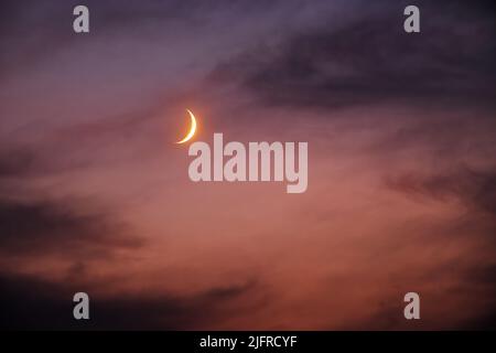 Luna in crescita in un cielo notturno drammatico tra le nuvole. Colori caldi della notte d'estate Foto Stock