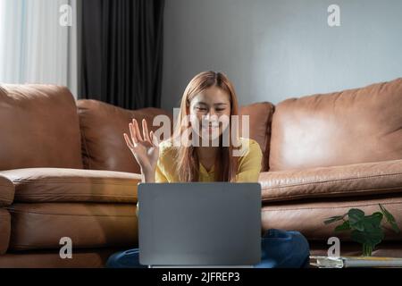 Attraente giovane studentessa asiatica che studia da remoto via computer portatile a casa, concetto di formazione online. Foto Stock