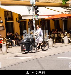 Monaco di Baviera,Germania-30 Giugno 2022:Una donna guida una bici da carico modificata che trasporta i bambini. Foto Stock