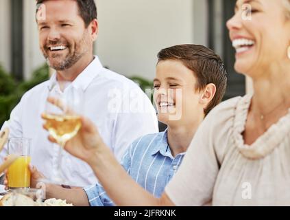 Festeggiamo le cose che più significano per noi. Shot di una famiglia che condivide un brindisi mentre si gusta un pasto insieme. Foto Stock