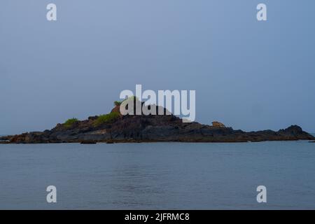 Erba sulle rocce. Rocce nel mezzo di un cielo oceano.chiaro con sfondo blu Foto Stock