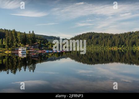 Atmosfera mattutina al lago Schluchsee nella Foresta Nera, riflessione d'acqua, noleggio barche e molo di spedizione in background, Baden-Wuerttemberg, Germania Foto Stock