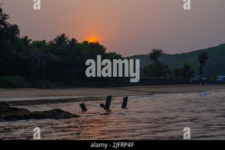 Legno in Seashore.Sunrise in om Beach.Golden luce riflettente Foto Stock