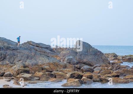 acqua limpida, il cielo blu del mare è limpido, l'uomo cammina sulle rocce Foto Stock