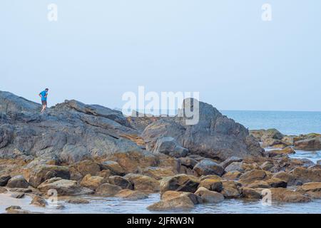 Grandi rocce a riva, uomo a piedi su rocce.cielo blu chiaro - Om spiaggia Karnataka Foto Stock