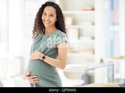 Sono entusiasta di questo mio nuovo viaggio. Ritratto di una donna d'affari incinta in piedi in un ufficio. Foto Stock