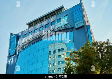 Facciata di vetro di edificio con alberi verdi, moderno edificio per uffici in citta' per societa' d'affari, residenziale contemporaneo Foto Stock