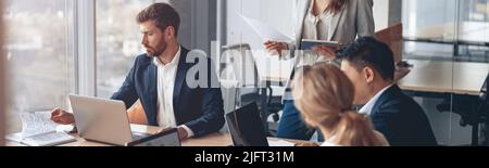 Giovani uomini d'affari che lavorano con i notebook in ufficio. Concetti di comunicazione e discussione sul lavoro Foto Stock