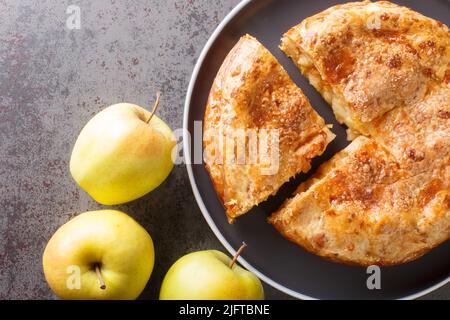 Torta di mele con crosta di formaggio primo piano nel piatto sul tavolo. Vista dall'alto orizzontale Foto Stock